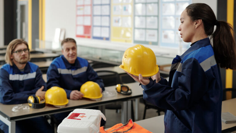 Female worker standing in front of colleagues while describing purpose of usage of protective helmet