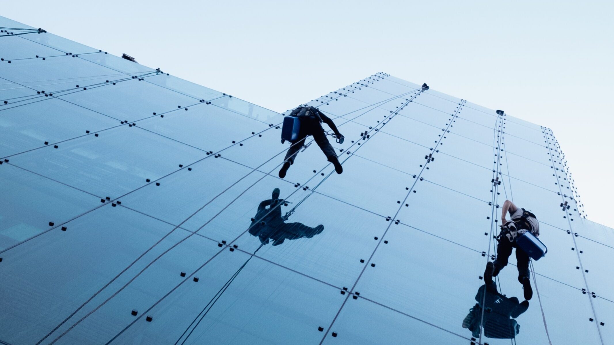 Low angle shot of two persons rappelling at the side of a tall building