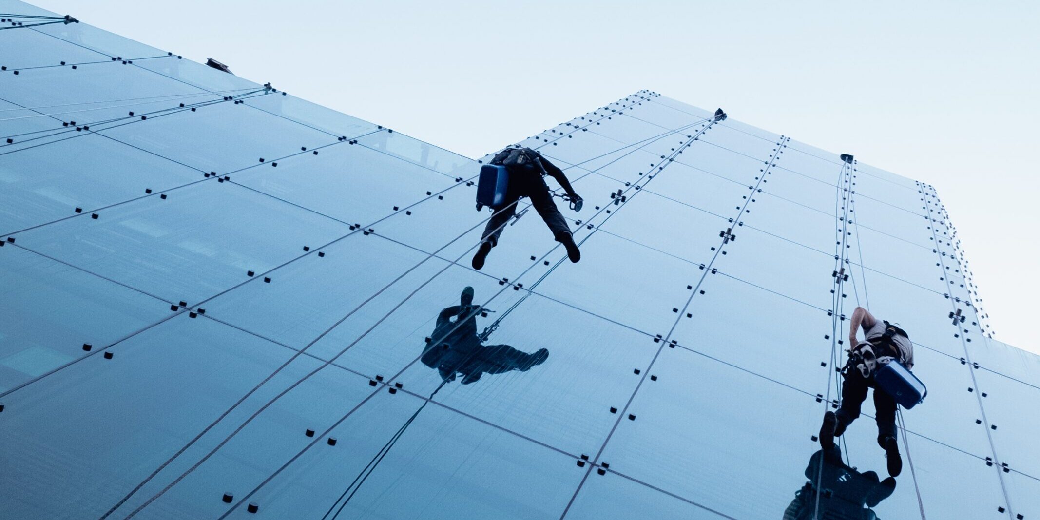 Low angle shot of two persons rappelling at the side of a tall building