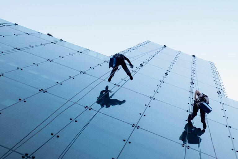 Low angle shot of two persons rappelling at the side of a tall building
